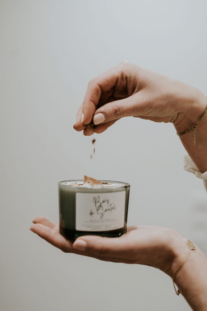 Artisan versant des botaniques sur une bougie Bois de Santal Atelier M