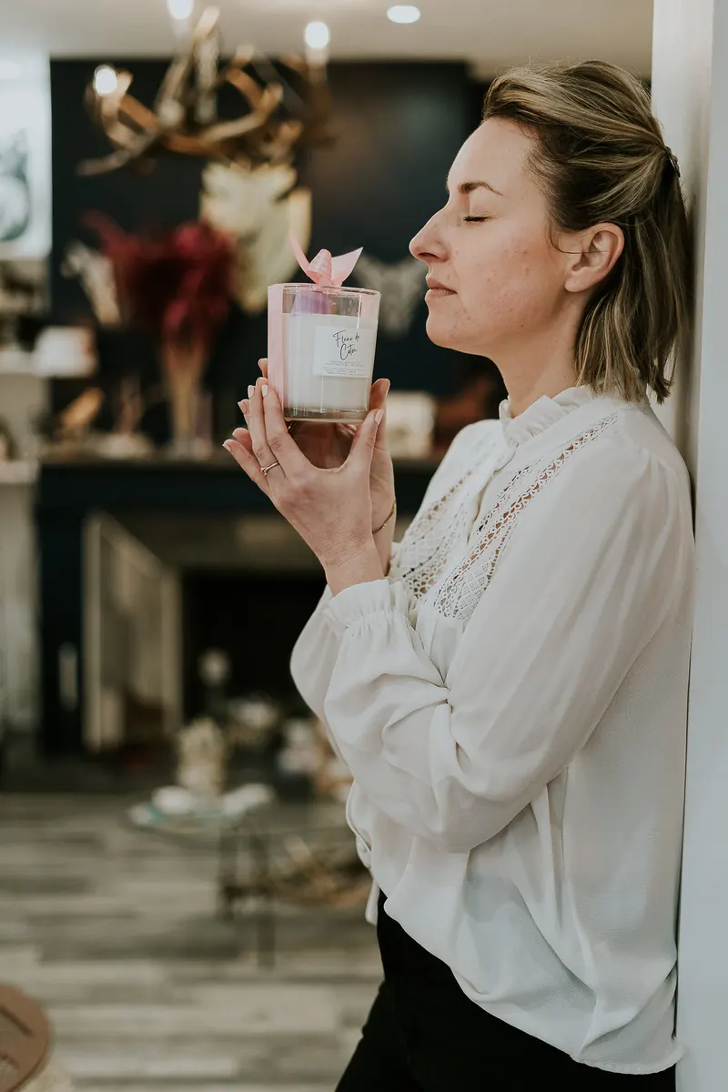 Margo sentant la bougie parfumée Fleur de Coton dans la boutique Atelier M